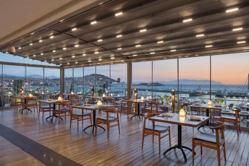 a restaurant with tables and chairs and windows at DoubleTree by Hilton Kusadasi in Kusadası