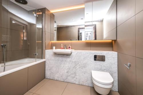 a bathroom with a toilet and a sink and a tub at Luxury 2 Bedroom Apartment in Tower Hill in London