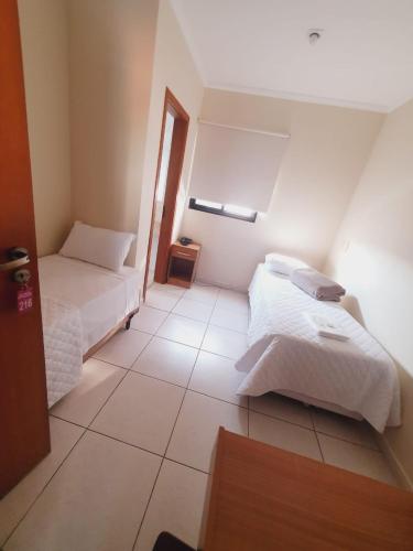 a bedroom with two beds and a tiled floor at Requinte Hotel in Sao Paulo