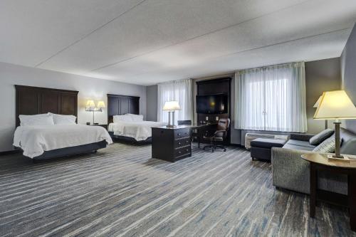 a hotel room with two beds a desk and a couch at Hampton Inn & Suites by Hilton Brantford in Brantford
