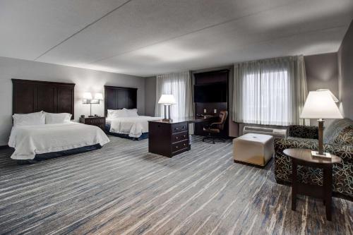 ブラントフォードにあるHampton Inn & Suites by Hilton Brantfordのベッド2台とシッティングエリアが備わるホテルルームです。