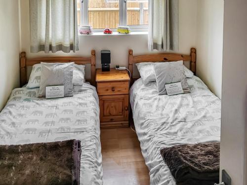 a bedroom with two beds and a dresser with windows at Little London in Bognor Regis