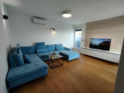 un salon avec un canapé bleu et une télévision dans l'établissement Seaside residence - Sunset Appartement, à Kožino