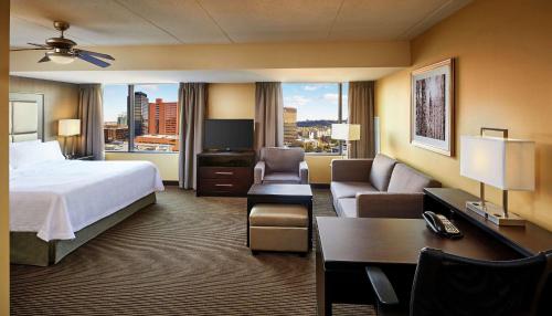 a hotel room with a bed and a couch and a desk at Homewood Suites by Hilton Hamilton in Hamilton