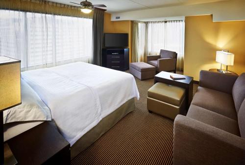 a hotel room with a bed and a couch and a chair at Homewood Suites by Hilton Hamilton in Hamilton