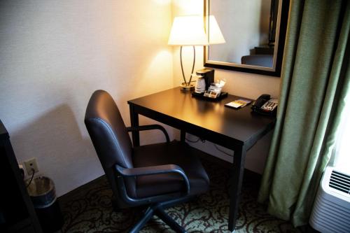 a desk in a hotel room with a lamp and a chair at Hampton Inn & Suites Sharon in West Middlesex