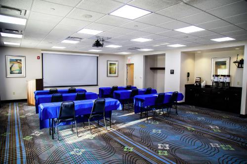 a conference room with blue tables and chairs and a white screen at Hampton Inn & Suites Sharon in West Middlesex