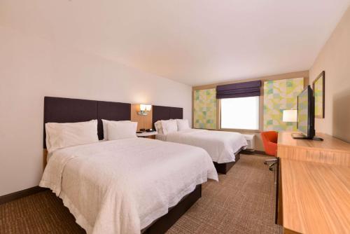 ein Hotelzimmer mit 2 Betten und einem Flachbild-TV in der Unterkunft Hampton Inn York in York