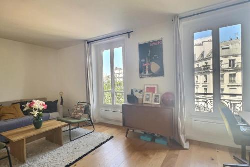 un salon avec un canapé et deux grandes fenêtres dans l'établissement Bright 34 m ideally located in Paris, à Paris