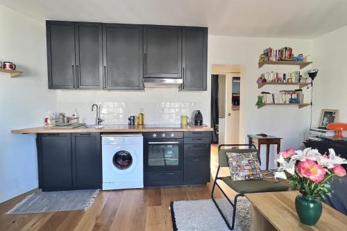 - une cuisine avec des armoires noires et un lave-linge dans l'établissement Bright 34 m ideally located in Paris, à Paris