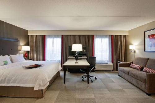 a hotel room with a bed and a desk and a couch at Hampton Inn & Suites by Hilton Toronto Markham in Markham