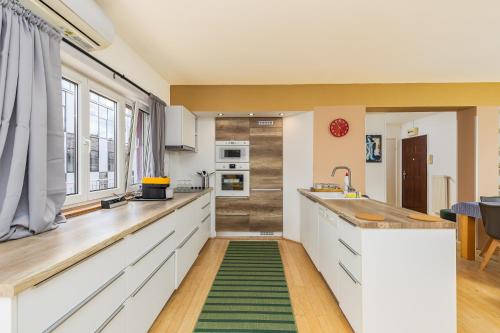a kitchen with white cabinets and a green rug on the floor at Center PENTHOUSE apartment - HUGE TERRACE and FREE PARKING - Tram/Metro - AC in Budapest