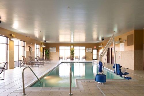een zwembad in een gebouw met tafels en stoelen bij Hampton Inn & Suites Vineland in Vineland