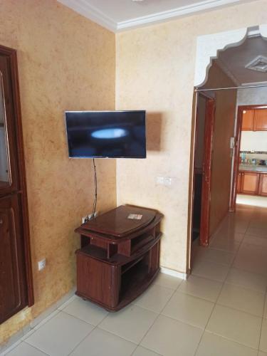 um quarto com uma televisão numa parede com uma mesa em إقامة الحمد em Meknès