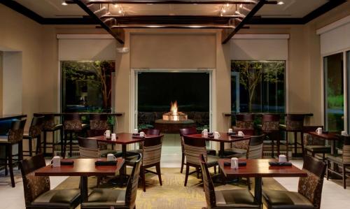 a restaurant with tables and chairs and a fireplace at Hilton Garden Inn Albany Airport in Albany