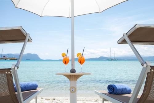 two chairs and an umbrella on the beach at Hotel Castello in Golfo Aranci