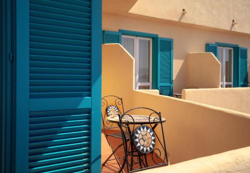 una mesa en el balcón de una casa con persianas azules en Hotel Castello, en Golfo Aranci
