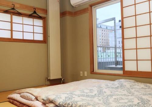 a bedroom with a bed and two windows at Kamome Building 3F - Vacation STAY 54301v in Otaru