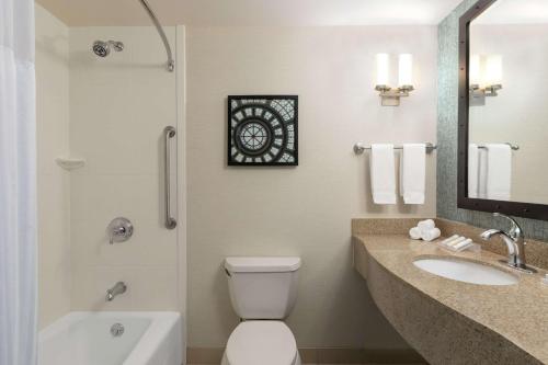 a bathroom with a toilet and a sink and a mirror at Hilton Garden Inn Troy in Troy