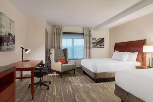 a hotel room with a bed and a desk and a bed and chair at Hilton Garden Inn Troy in Troy