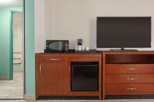 a television on top of a wooden dresser with a microwave at Hilton Garden Inn Troy in Troy