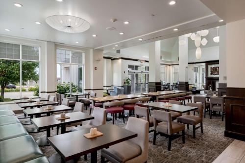 een restaurant met tafels, stoelen en ramen bij Hilton Garden Inn Ames in Ames