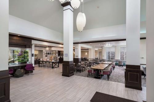 een lobby met tafels en stoelen en een restaurant bij Hilton Garden Inn Ames in Ames