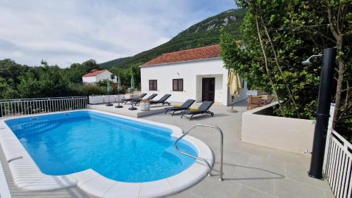 a swimming pool with chairs and a house at Villa Paradise Garden in Ston