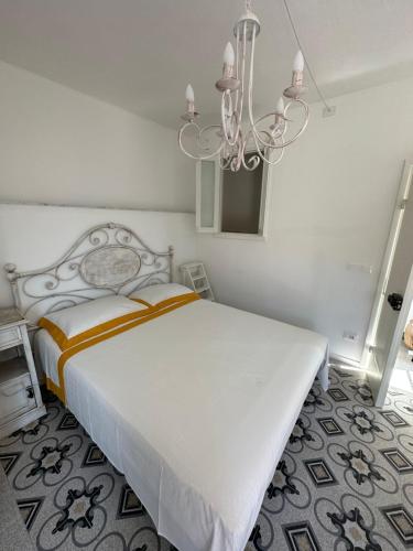 um quarto com uma cama branca e um lustre em Favolosa stanza gialla con terrazzino vista mare Mottino23 em Lerici