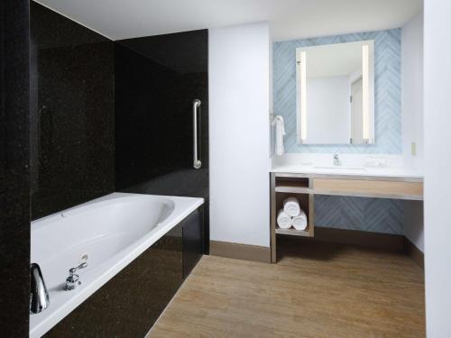 a bathroom with a tub and a sink and a mirror at Hilton Garden Inn Atlanta NW/Kennesaw-Town Center in Kennesaw