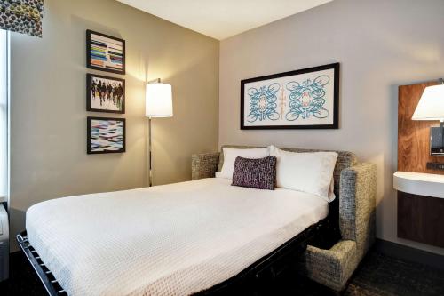 a small bedroom with a bed and a chair at Hampton Inn Atlanta-Mall Of Georgia in Buford