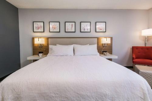 a bedroom with a large white bed and a red chair at Hilton Garden Inn Atlanta Marietta in Atlanta