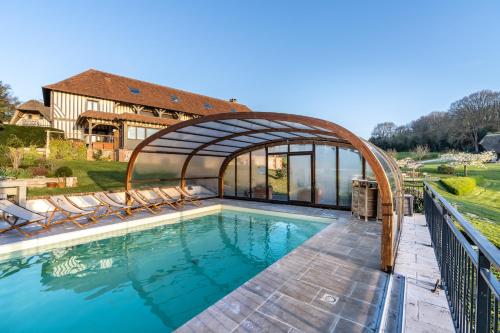 a swimming pool with an archway and a house at B&B Le Clos du Phare - En campagne in Saint-Samson-de-la-Roque