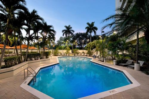 a large swimming pool with palm trees in a resort at Embassy Suites Boca Raton in Boca Raton
