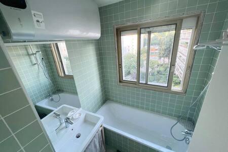 une salle de bain avec une baignoire, un lavabo et une fenêtre dans l'établissement Entiry apartment, Private rooms in Paris, à Paris