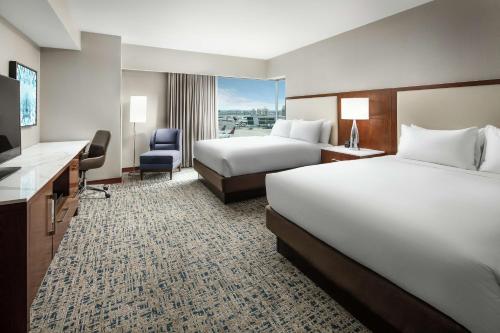 a hotel room with two beds and a desk at Hilton Boston Logan Airport in Boston