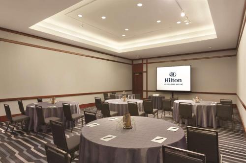 a conference room with tables and chairs and a screen at Hilton Boston Logan Airport in Boston