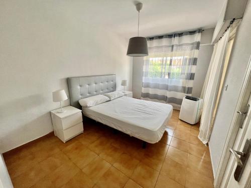 sypialnia z białym łóżkiem i oknem w obiekcie Bungalow in San Juan Playa w mieście Benimagrell