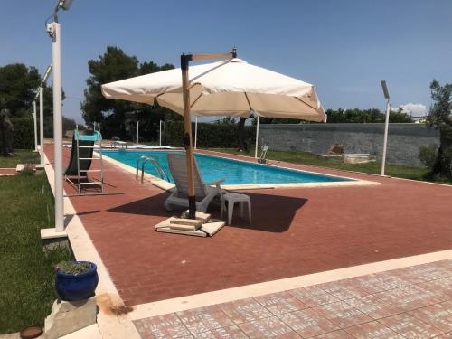 a pool with an umbrella and two chairs and a pool at Sans-souci in Nardò