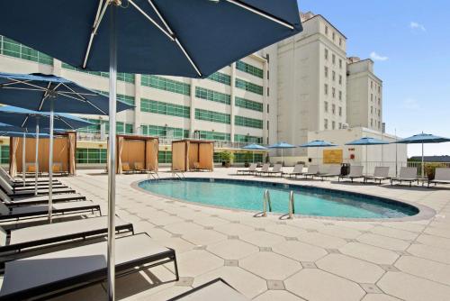 uma piscina com cadeiras e guarda-sóis em frente a um edifício em Hilton Baton Rouge Capitol Center em Baton Rouge