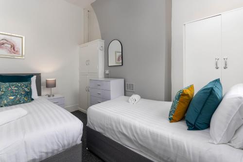 two beds in a room with white walls and blue pillows at Woodbine House - Air Host and Stay - Free parking - Contractor Friendly in Liverpool