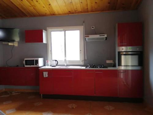a kitchen with red cabinets and a window at LE MACADAMIA in Cilaos