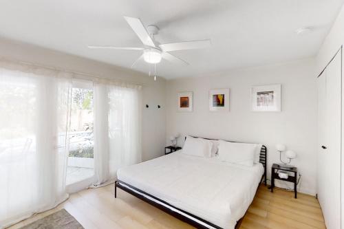 a white bedroom with a bed and a ceiling fan at Modern Oasis in Sarasota