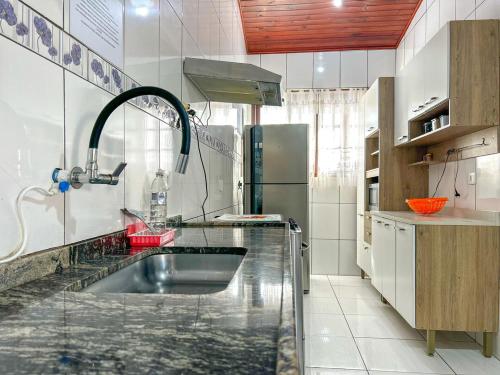 La cuisine est équipée d'un évier et d'un réfrigérateur. dans l'établissement Otima casa com WiFi e churrasqueira em Bertioga SP, à Bertioga