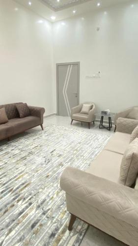 a living room with couches and chairs in a room at Al Saad chalet in Al Ashkharah