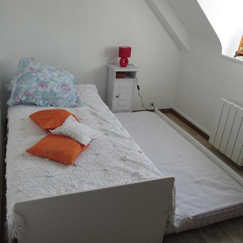 un lit avec un oreiller orange et un vase rouge dans l'établissement Kerbarbo, à Plouagat