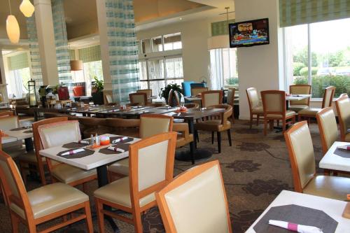 a dining room with tables and chairs and a television at Hilton Garden Inn Addison in Addison
