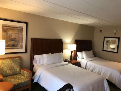 a hotel room with two beds and a chair at Hilton Garden Inn Addison in Addison