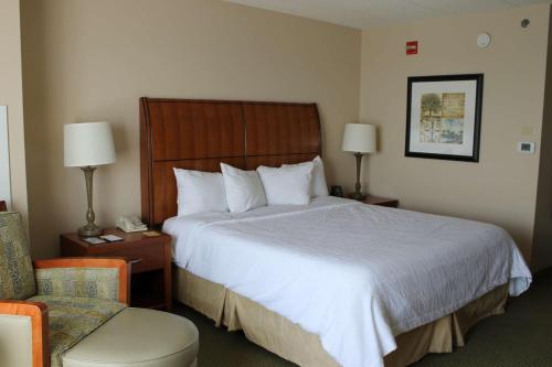 a hotel room with a large bed and a chair at Hilton Garden Inn Addison in Addison