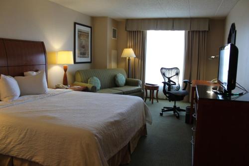 a hotel room with a bed and a television at Hilton Garden Inn Addison in Addison